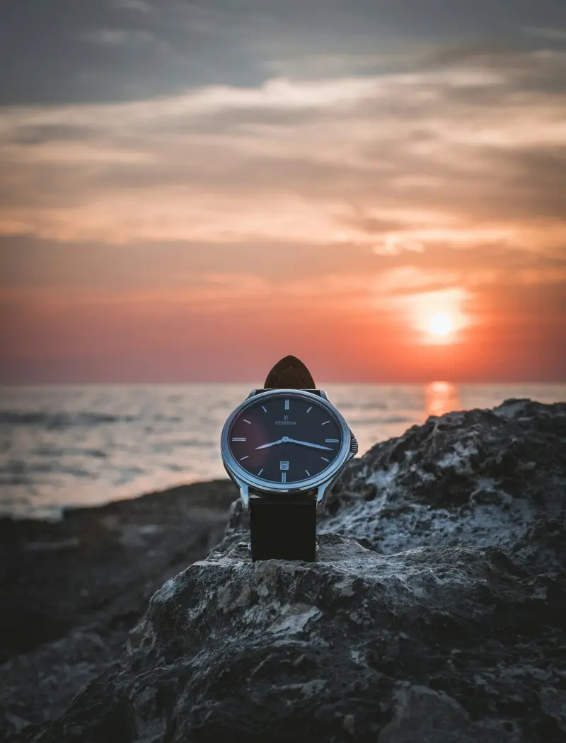 A dive watch with a rotating bezel resting on dark stone